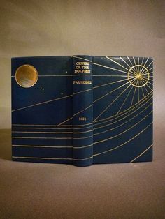 an open book with gold lines on the cover and blue paper in front of it