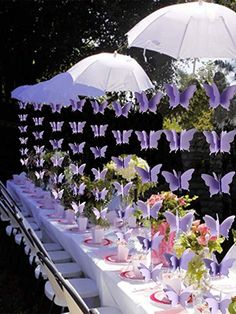 a long table covered with white umbrellas and purple butterflies on the wall behind it