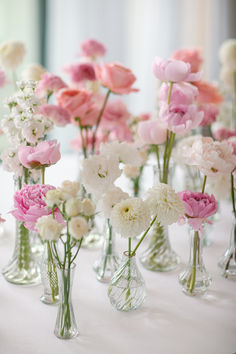 there are many vases with flowers in them on the tableclothed table cloth