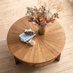 a wooden table with a vase and some flowers on top of it next to a magazine