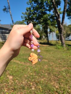 a person holding onto some charms in their hand on the grass with trees in the background