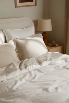 an unmade bed with white sheets and pillows