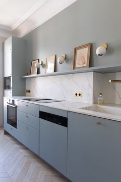 a kitchen with gray cabinets and marble counter tops, gold pulls on the faucet