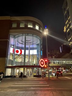 an intersection at night with traffic lights and buildings in the background