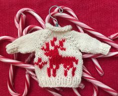 a knitted sweater ornament with candy canes around it