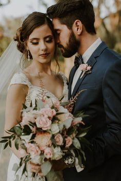 a bride and groom pose for a wedding photo in front of some trees with pink flowers