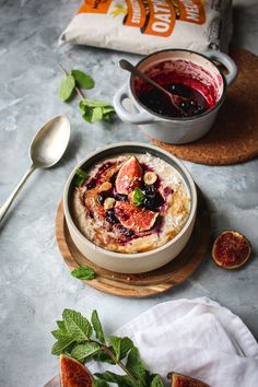 a bowl of oatmeal with figs and mint leaves on the side