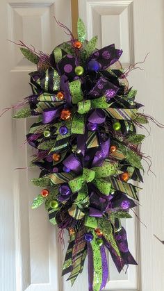 a purple and green wreath hanging on the front door with halloween decorations around it's edges