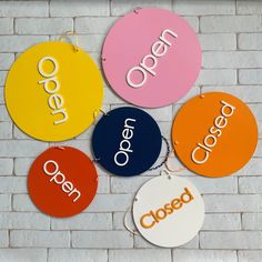 four circular signs with the words open and closed hanging on a brick wall