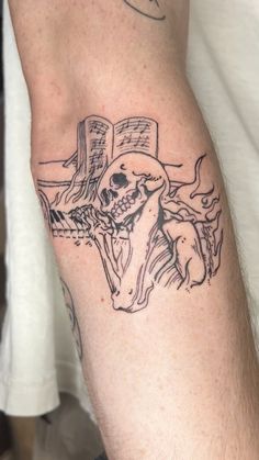 a man with a tattoo on his arm has a cross and a skull in it