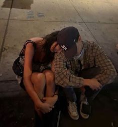 a man and woman sitting on the ground next to each other with their arms around each other