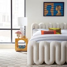 a white bed sitting in a bedroom next to a window with large panoramic windows