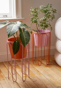 two planters with plants in them sitting on the floor next to each other near a window