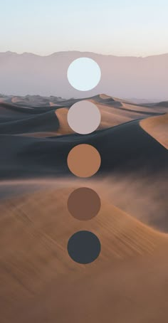 the desert is filled with sand dunes and mountains in the distance are three circles that appear to be different colors