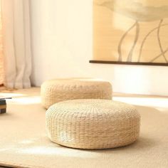 two wicker stools sitting on top of a rug in front of a painting