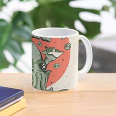 a coffee mug with an octopus on it sitting on a table next to some books