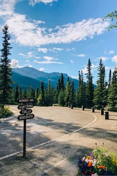 there are many signs on the road pointing to different places in the woods and mountains