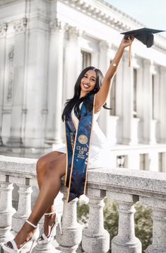 a woman is sitting on a balcony with her graduation cap in the air