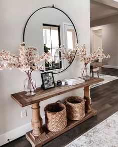 there is a mirror and some flowers on the shelf in front of the console table