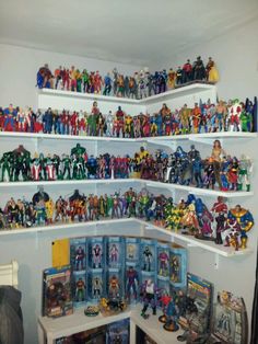 a room filled with lots of toy action figures and toys on top of white shelves