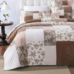 a bed covered in a brown and white quilted comforter next to a night stand