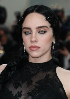 a woman with dark hair and blue eyes wearing black lace on top of her head