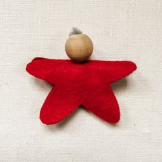 a red star ornament with a wooden ball on it's top, sitting on a white surface