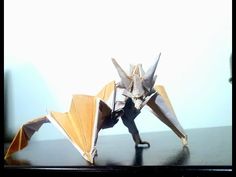 an origami dragon on a table with its wings folded back and legs extended