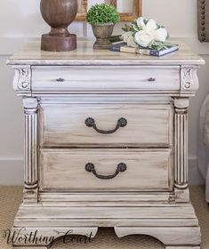 a white dresser with two drawers and flowers on top