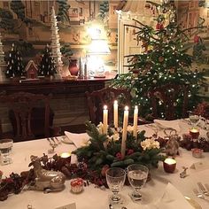 a dining room table is set for christmas dinner with candles and decorations on the table