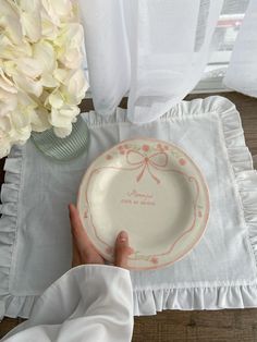 a person holding a plate on top of a table next to a vase with flowers