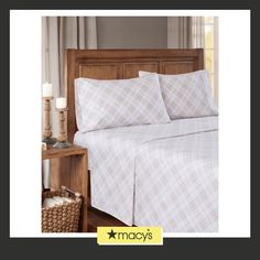 an image of a bed with white sheets and plaid pattern on it in a bedroom