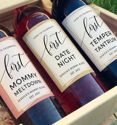 three bottles of wine sitting in a wooden box next to each other on the grass