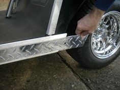 a person is holding onto the side of a vehicle with chrome wheels and rims