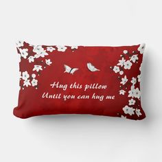 a red pillow with white flowers and two birds on it that says, hang this pillow until you can hug me