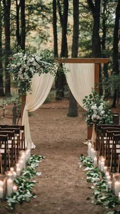 an outdoor ceremony setup with white flowers and greenery on the aisle, lit by candles