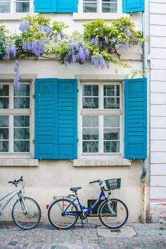 two bikes parked next to each other in front of a building with blue shutters