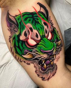 a green and black tiger tattoo on the right side of the thigh, with red eyes