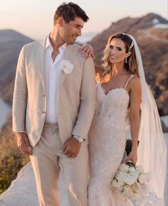 a bride and groom standing on top of a mountain