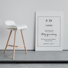 a white bar stool next to a black and white poster