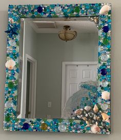 there is a mirror that has shells on it and sea glass in the bottom half