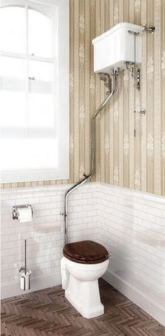 a white toilet sitting next to a window in a bathroom with wooden floors and walls