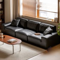 a living room with a black leather couch and coffee table in front of a window