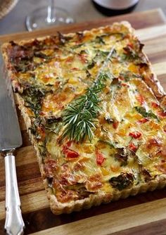 a quiche on a cutting board with a knife and fork