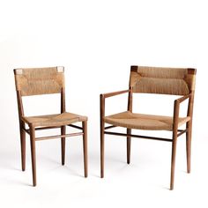 two wooden chairs sitting next to each other on a white surface with no one in it