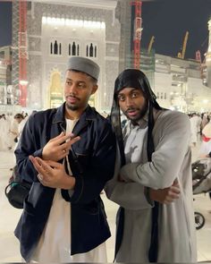 two men standing next to each other in front of a building