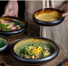 three bowls filled with food on top of a wooden table next to two people holding plates