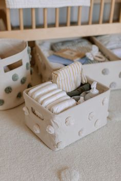 an open box sitting on top of a bed next to a baby crib with clothes in it