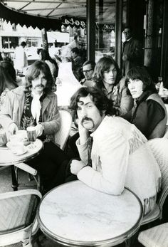 a group of people sitting at tables in front of a building with plates on them