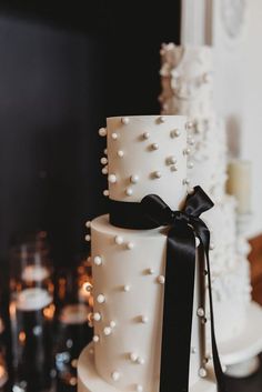 a white and black wedding cake with pearls on it